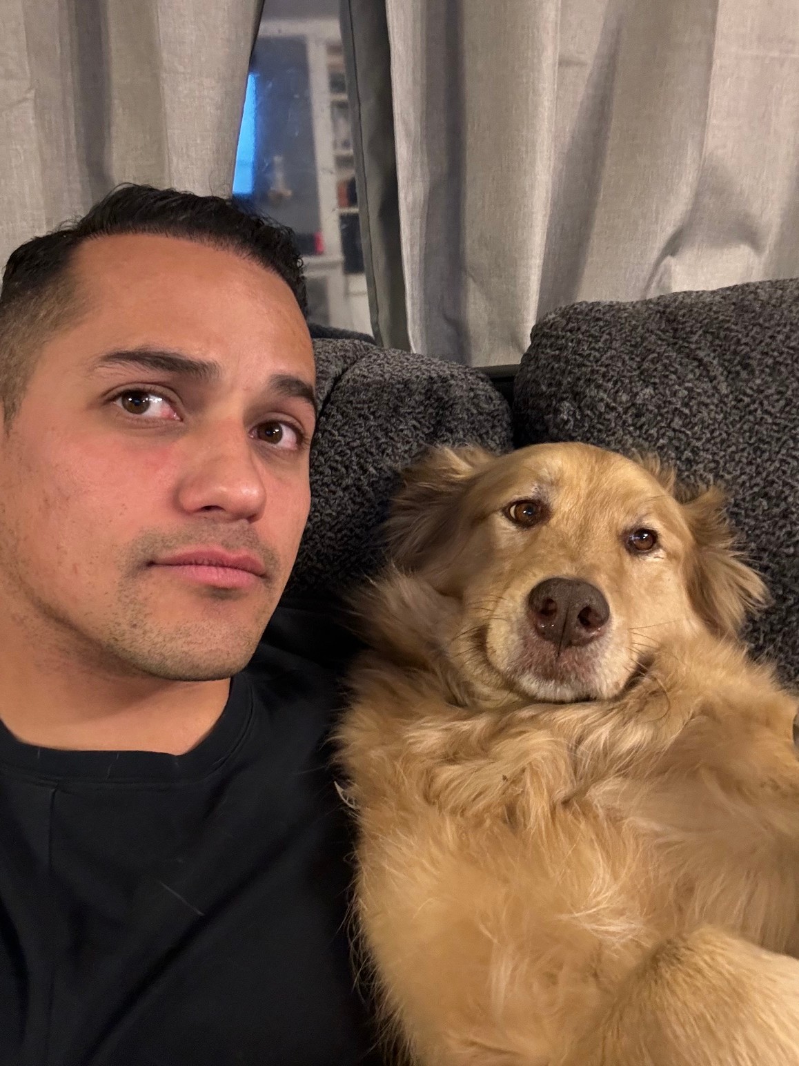 Luis Banda relaxing on the couch with his golden retriever mix